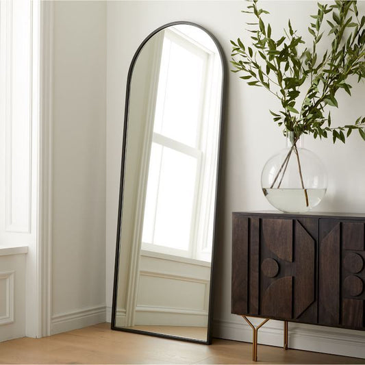Modern home interior showing a tall arched mirror and dark wood luxury furniture for how to choose luxury furniture for home