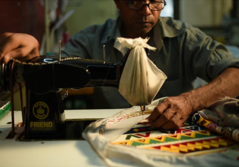 Craftsman sewing colorful fabric using a sewing machine representing sustainable home decor brands