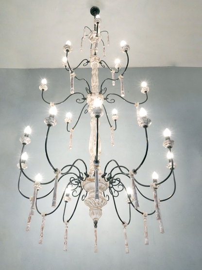 Chic French Country 21 Lights 3 Tier Rustic White Wood and Wrought iron Candelabra Chandelier with lights on and placed in a home